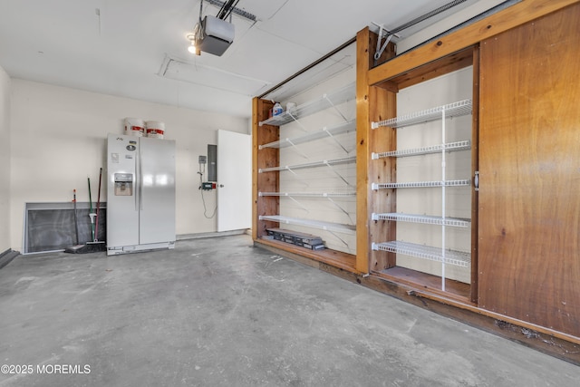 garage with a garage door opener and white fridge with ice dispenser