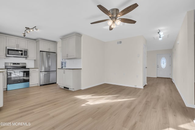 kitchen with ceiling fan, tasteful backsplash, stainless steel appliances, and light hardwood / wood-style flooring