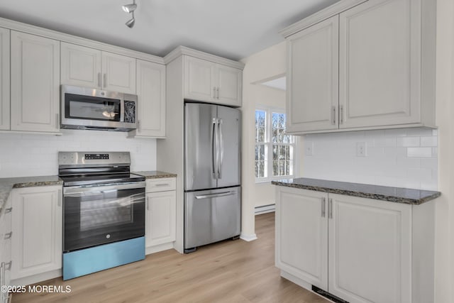 kitchen with white cabinets, dark stone countertops, stainless steel appliances, and light hardwood / wood-style floors