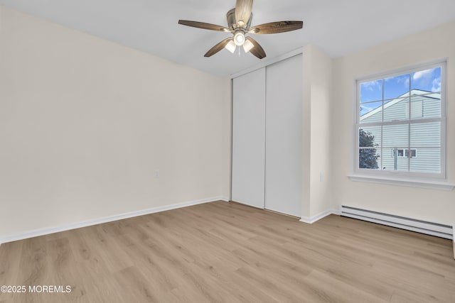 unfurnished bedroom with ceiling fan, light wood-type flooring, a closet, and a baseboard radiator