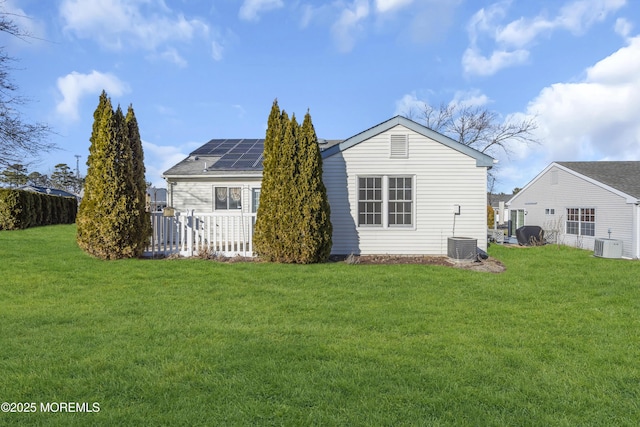 back of property with a yard and solar panels