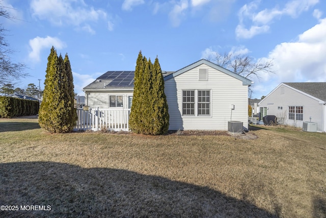 back of property with a yard, solar panels, and central AC unit