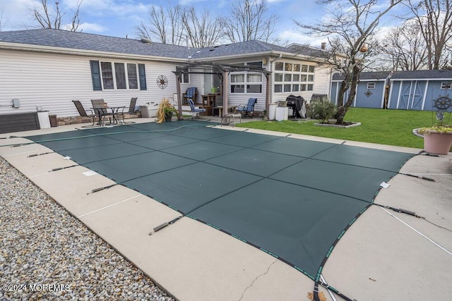 view of swimming pool featuring a shed, a patio, a lawn, area for grilling, and a pergola