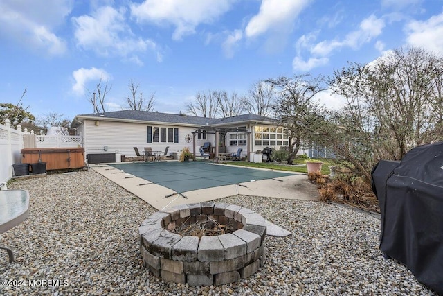 rear view of house with central AC, a hot tub, a fire pit, and a patio