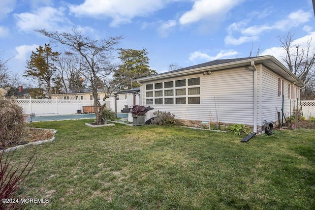 rear view of property with a swimming pool and a lawn