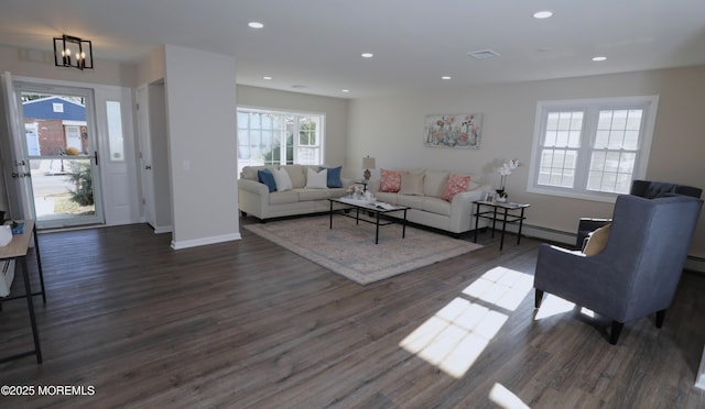 living room with a baseboard heating unit, a chandelier, and dark wood-type flooring