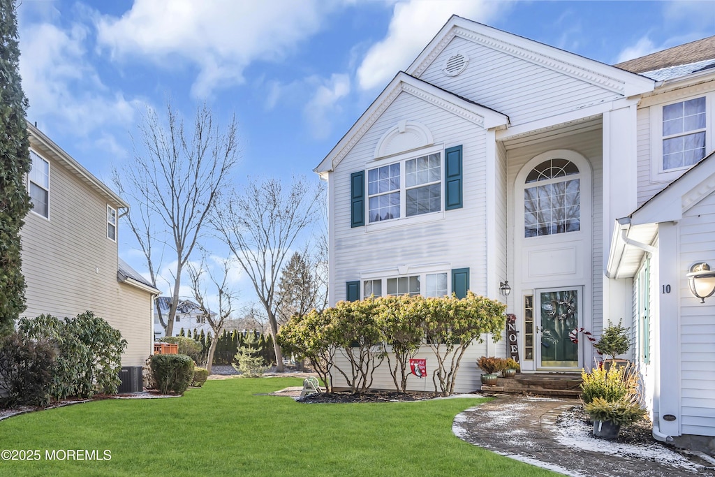 view of front of property with a front lawn and central AC