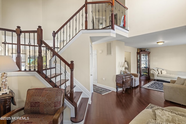 staircase with a towering ceiling and hardwood / wood-style flooring