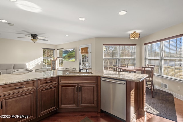 kitchen with sink, light stone counters, ceiling fan, stainless steel dishwasher, and dark wood-type flooring