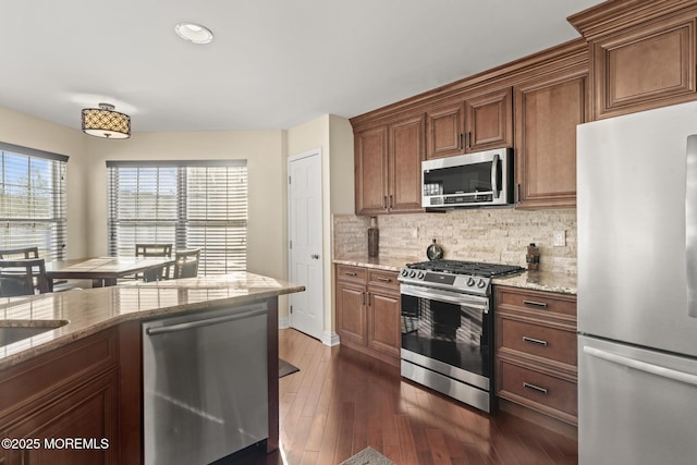 kitchen featuring light stone counters, appliances with stainless steel finishes, dark hardwood / wood-style flooring, and decorative backsplash