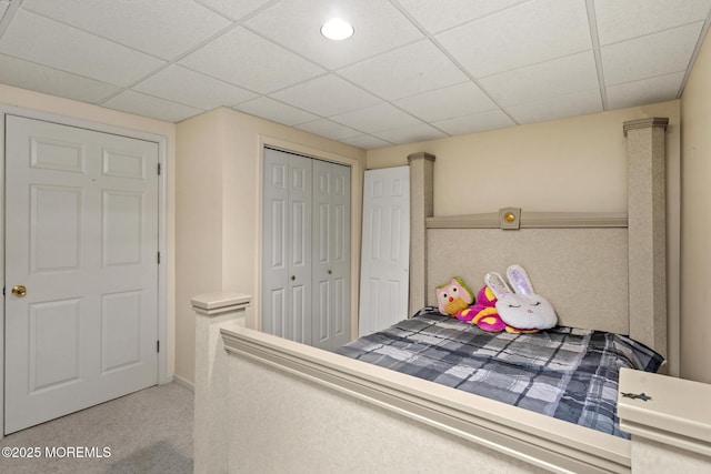 unfurnished bedroom with light colored carpet, a closet, and a paneled ceiling