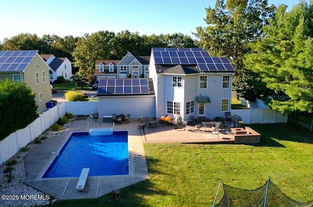 rear view of house with solar panels, a patio, a pool side deck, and a lawn