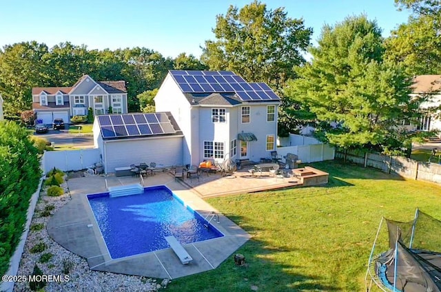 back of house featuring a yard, an outbuilding, solar panels, a fenced in pool, and a patio area