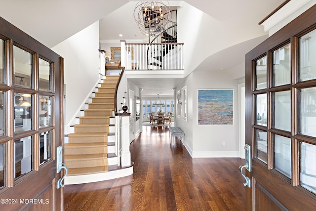 entryway with a towering ceiling, hardwood / wood-style flooring, and a notable chandelier