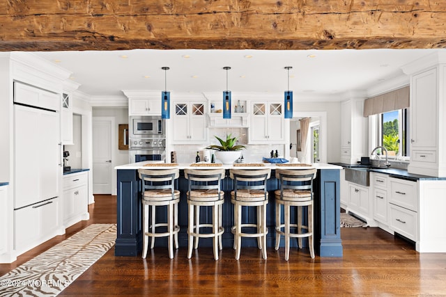 kitchen with a kitchen island, sink, built in appliances, and hanging light fixtures