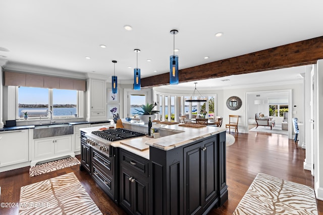 kitchen with hanging light fixtures, a center island with sink, beam ceiling, white cabinets, and sink