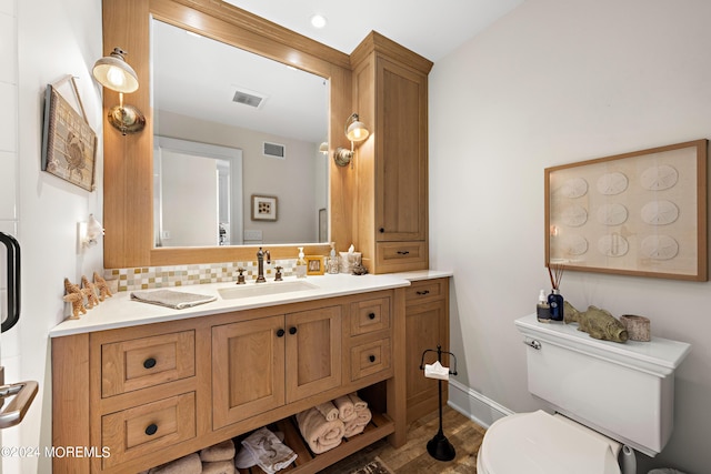 bathroom with toilet, vanity, hardwood / wood-style floors, and backsplash