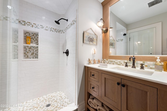 bathroom featuring a tile shower, vanity, and tasteful backsplash