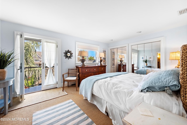 carpeted bedroom featuring access to outside and two closets