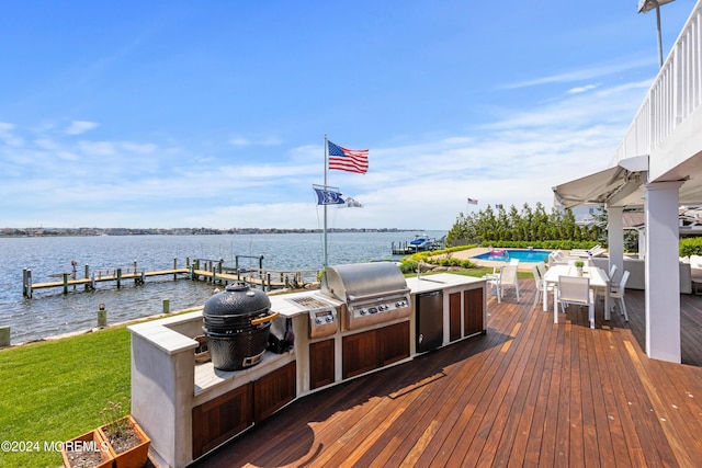 wooden deck featuring a water view, exterior kitchen, and grilling area