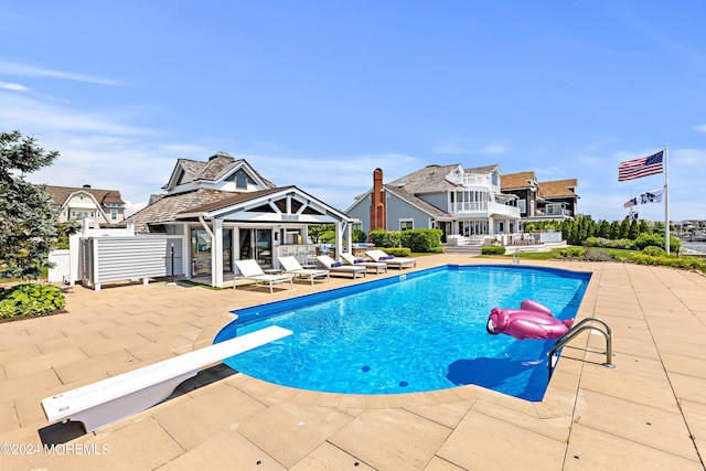 view of swimming pool with a patio and a diving board