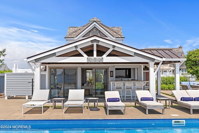 exterior space featuring an outbuilding, a bar, outdoor lounge area, and a patio