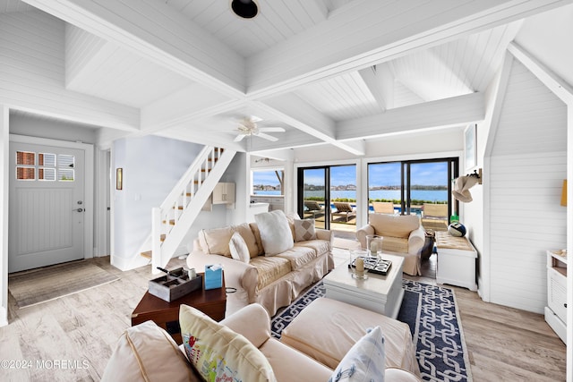 living room featuring ceiling fan, light hardwood / wood-style flooring, beamed ceiling, and a water view