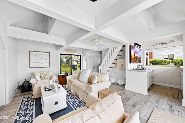 living room with ceiling fan, light hardwood / wood-style flooring, beamed ceiling, and plenty of natural light