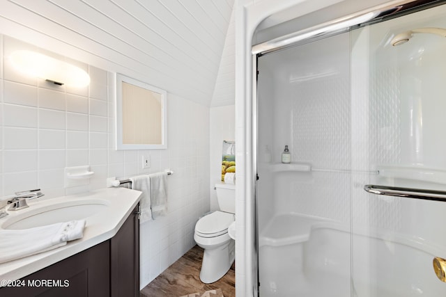 bathroom with tile walls, toilet, wood-type flooring, a shower with door, and vanity