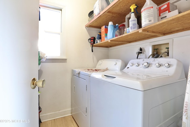 clothes washing area with washer and clothes dryer and light wood-type flooring