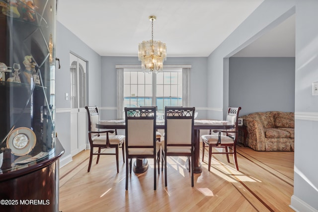 dining area with light wood-type flooring and a notable chandelier