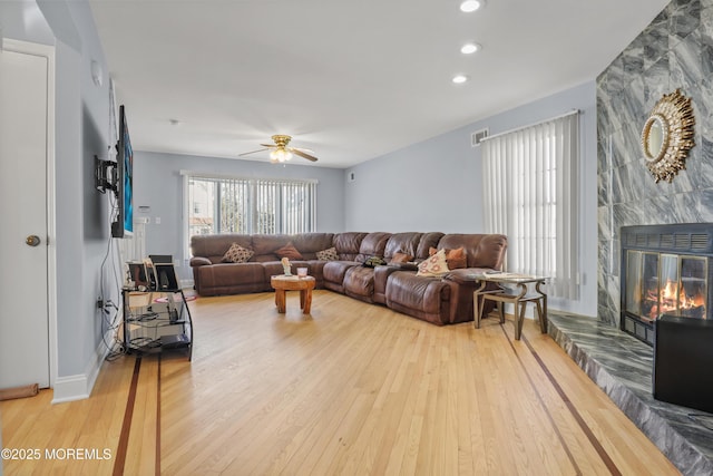 living room featuring a fireplace, ceiling fan, and light hardwood / wood-style flooring