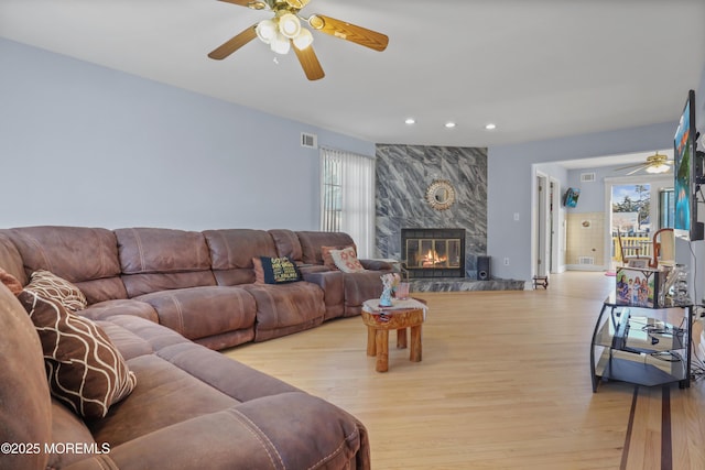 living room with a high end fireplace, light hardwood / wood-style flooring, and a wealth of natural light