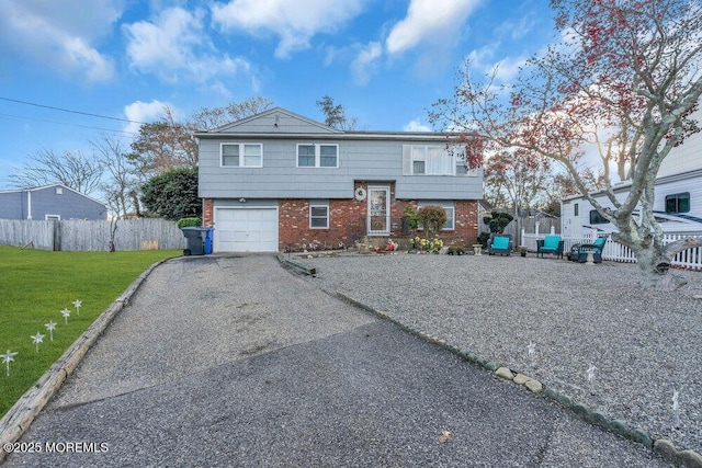 raised ranch featuring a garage and a front lawn