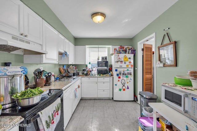 kitchen featuring white appliances, white cabinetry, light stone countertops, and sink