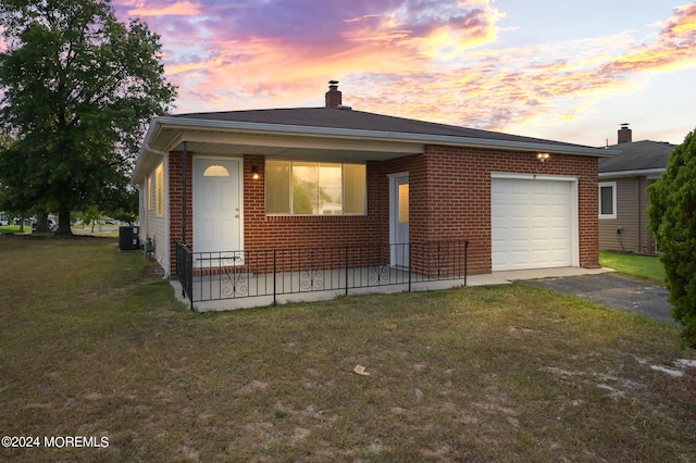 view of front of home featuring central AC, a lawn, and a garage