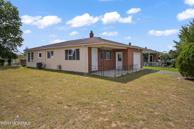 rear view of property featuring a lawn, central AC unit, and a garage