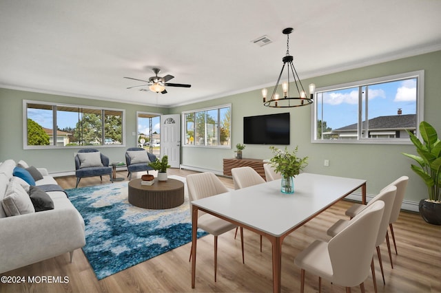 dining room with ornamental molding, baseboard heating, light hardwood / wood-style flooring, and ceiling fan with notable chandelier