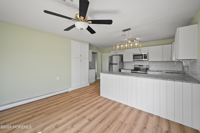 kitchen featuring white cabinets, stainless steel appliances, hanging light fixtures, kitchen peninsula, and sink