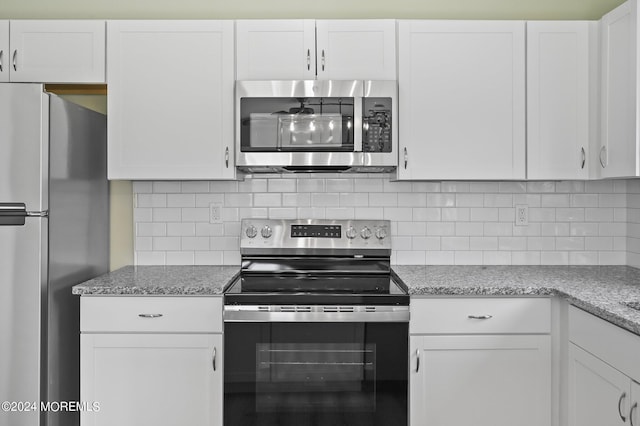 kitchen featuring stainless steel appliances, white cabinets, decorative backsplash, and light stone counters