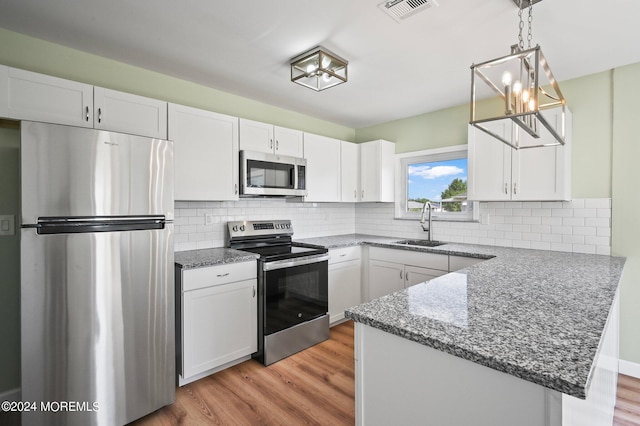 kitchen with kitchen peninsula, white cabinets, and appliances with stainless steel finishes