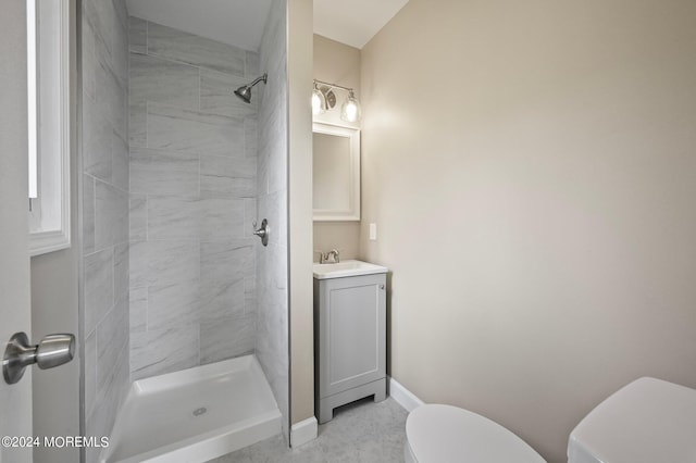 bathroom featuring toilet, tiled shower, and vanity