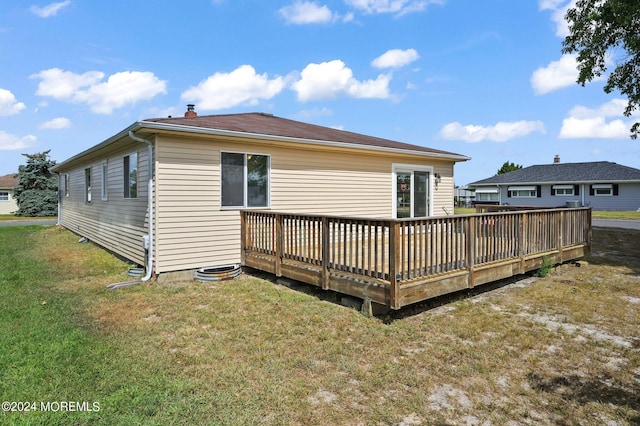 back of property featuring a deck and a lawn