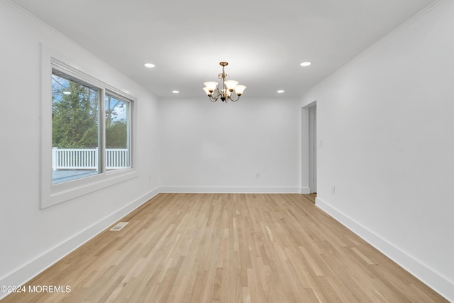 unfurnished room featuring ornamental molding, an inviting chandelier, and light hardwood / wood-style floors