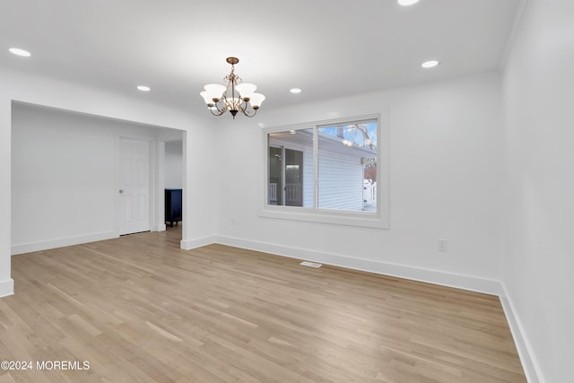 empty room featuring an inviting chandelier and light wood-type flooring