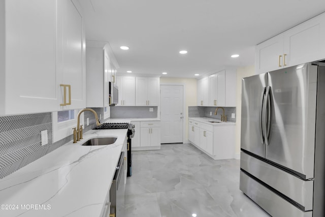 kitchen with appliances with stainless steel finishes, white cabinetry, light stone countertops, and decorative backsplash