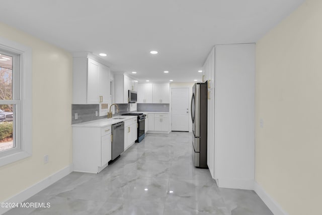 kitchen with sink, white cabinets, tasteful backsplash, and appliances with stainless steel finishes