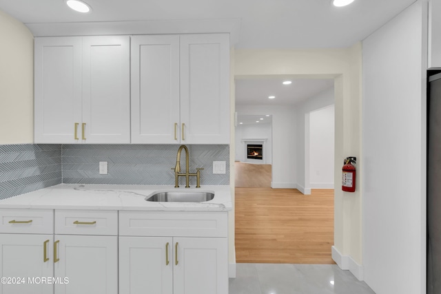 kitchen featuring sink, white cabinets, tasteful backsplash, and light stone counters