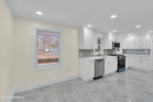 kitchen featuring stainless steel appliances, white cabinets, sink, and backsplash