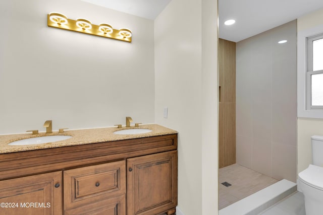 bathroom featuring toilet, vanity, tile patterned flooring, and tiled shower